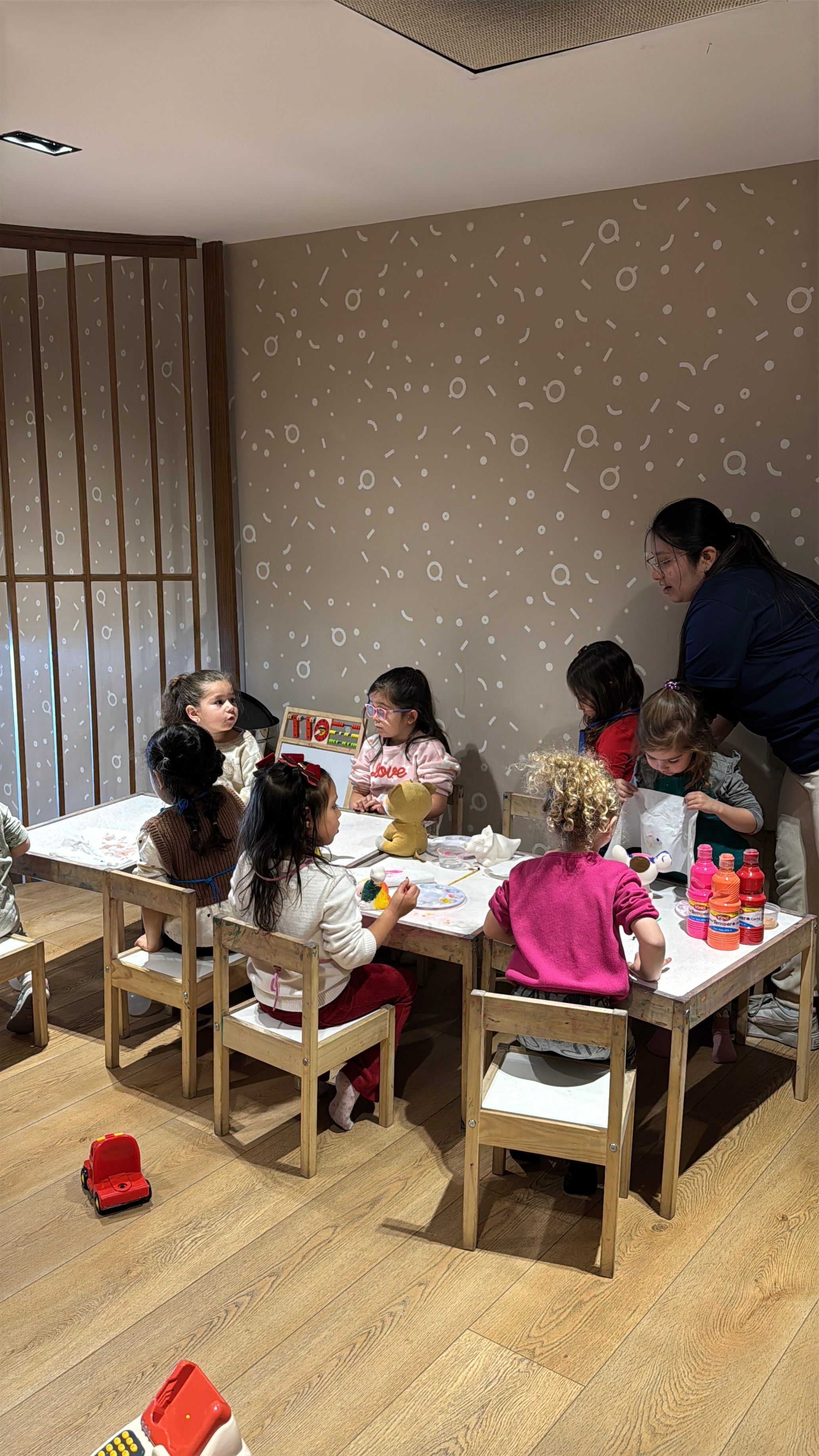 Niños en la mesa de una fiesta infantil en Cofki, con una nanny acompañando