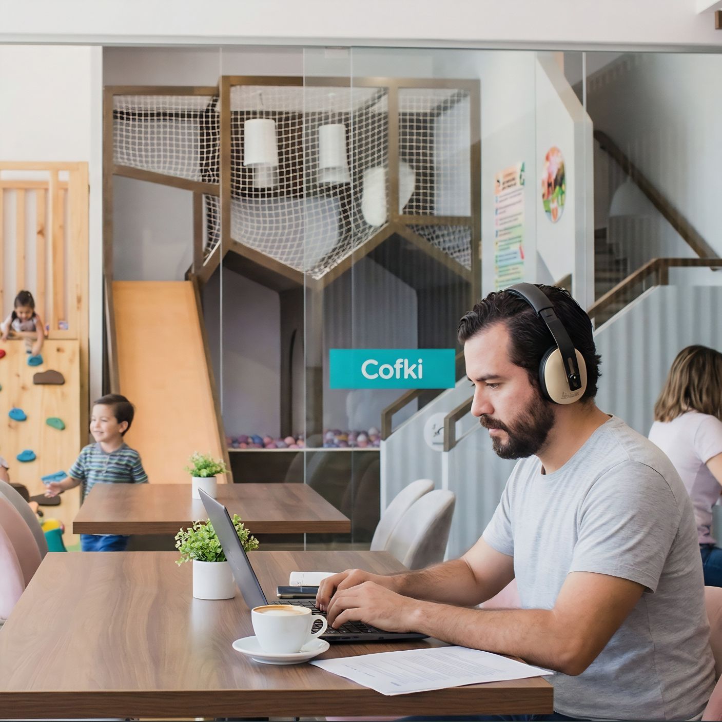 Mamá trabajando con su laptop en el coworking de Cofki mientras sus hijos juegan cerca